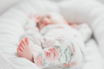 婴儿穿着白色和红色的花朵睡衣躺在床上